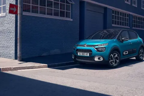 Citroën C3 bleue garée sur le trottoir, avec un panneau de signalisation. La taille pneu Citroën C3 est adaptée à ce modèle urbain.