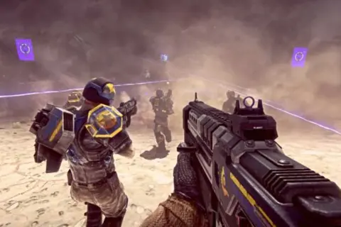 Gracze w futurystycznych zbrojach walczą na pustynnym polu bitwy. To jedna z najlepszych gier na PS4, pełna akcji i emocji.