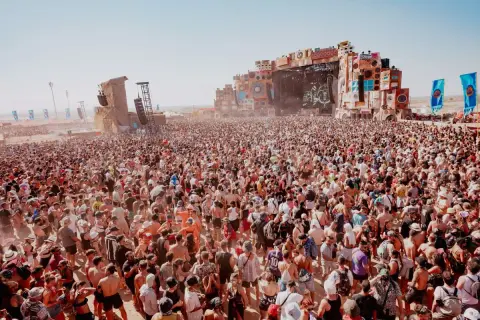 Multitudinaria asistencia al Monegros Festival, con miles de personas disfrutando de la música y el ambiente bajo un sol radiante.