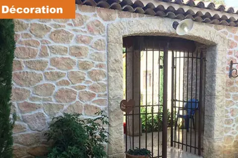 Maison avec un bel enduit pierre apparente, une arche et une grille rouillée.