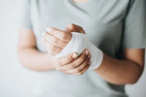 Dłoń z bandażem, wspierająca proces gojenia ran. Odpowiednia dieta na gojenie ran przyspieszy powrót do zdrowia.