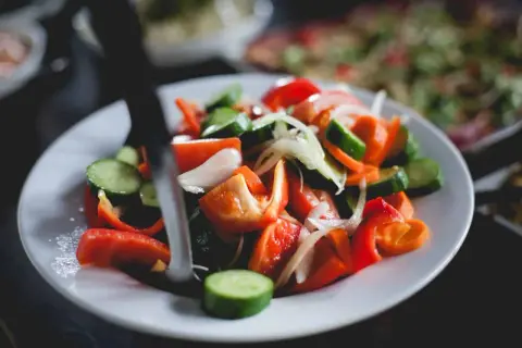 Kolorowa sałatka z pomidorów, ogórków, papryki i cebuli. To przykład tego, co to jest weganizm – dieta oparta na roślinach.