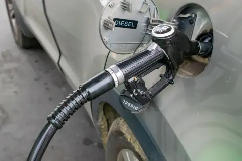 Tankowanie diesla. Zbliżenie na pistolet paliwowy wlewu paliwa samochodu. Informacja o rodzaju paliwa "DIESEL" jest widoczna.