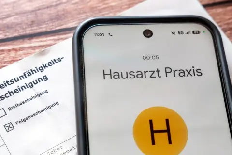 Arbeitsunfähigkeitsbescheinigung liegt bereit. Das Handy zeigt Anruf bei Hausarzt Praxis. Wichtig für Krankmeldung ab 3. Tag Gesetz.