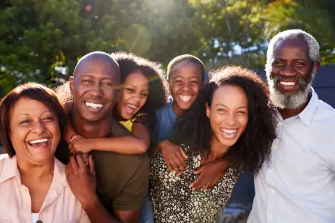 Una familia multigeneracional sonríe y ríe junta al aire libre, disfrutando de actividades de día familiar.