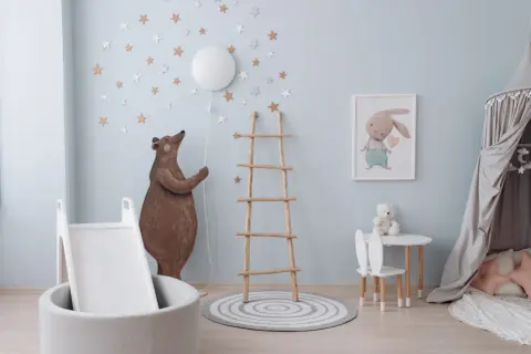 Douce couleur peinture chambre bébé bleu ciel, décorée d'étoiles et d'un ours. Un coin jeu avec toboggan et tapis.