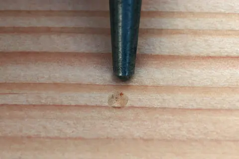 Ein Metallstift markiert eine Stelle auf Holz, bereit zum schamottstein bohren.