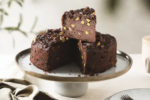 Torta di pane al cioccolato, ricca e golosa, con pistacchi e cacao, servita su un'alzata.