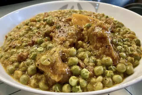 Un saporito spezzatino con piselli, teneri pezzi di carne e verdure in un sugo denso e profumato, pronto per essere gustato.