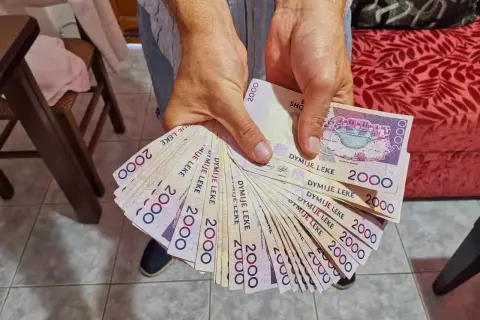 Hände halten einen Fächer aus albanischem Geld, 2000 Lek-Scheine.