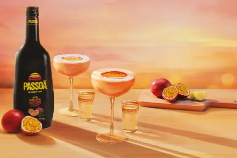 Passoa to alkohol z marakui. Butelka likieru, drinki i świeże owoce na tle zachodzącego słońca.