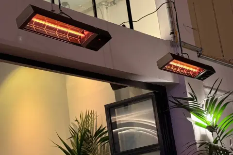 Dwa wiszące promienniki ciepła elektryczne emitują przyjemne, pomarańczowe światło, ogrzewając przestrzeń.