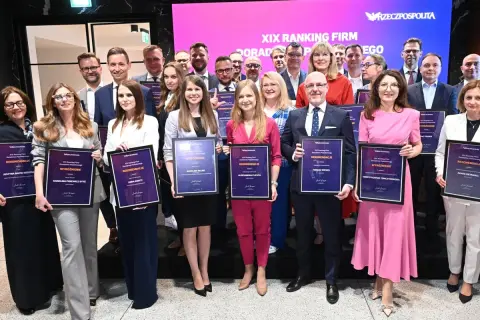 Grupa osób w eleganckich strojach pozuje z dyplomami na tle sceny z logo "Rzeczpospolita".