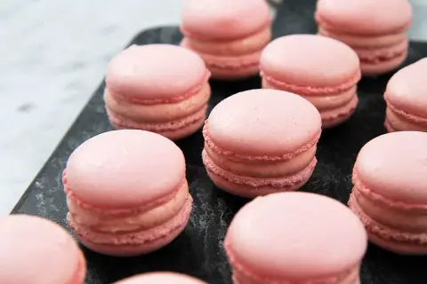 Rosa macarons på en mörk yta, perfekta för ett macarons recept.