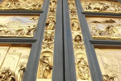 Detalle de las puertas del paraíso, con relieves dorados que narran escenas bíblicas y figuras alegóricas.