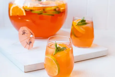 Erfrischende Aperol Bowle mit Orangen- und Limettenscheiben, garniert mit Minze. Perfekt für heiße Sommertage.