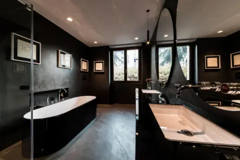 Elegantes, dunkles Badezimmer mit freistehender schwarzer Wanne, Doppelwaschbecken und moderner Spiegelarchitektur.