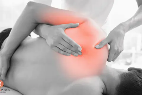 Physiotherapeut behandelt Schmerzen im Schulterbereich, wo ein nerv eingeklemmt sein könnte. Rote Bereiche zeigen die schmerzende Zone.