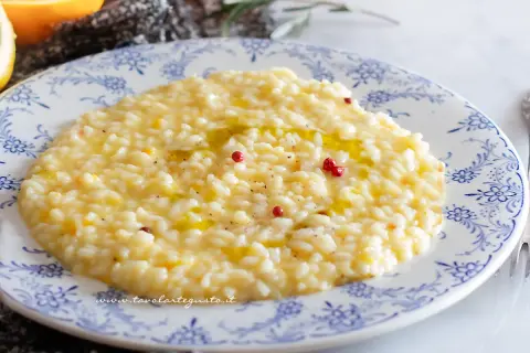 Un cremoso risotto al limone gourmet, guarnito con pepe rosa e un filo d'olio, pronto per essere gustato.