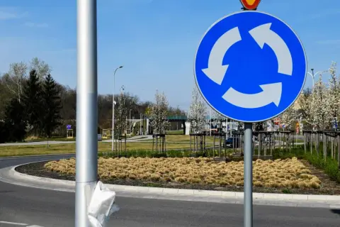 Znak informuje, kto ma pierwszeństwo na rondzie. Trzy białe strzałki na niebieskim tle wskazują kierunek ruchu i sugerują, że pojazdy na rondzie mają pierwszeństwo.