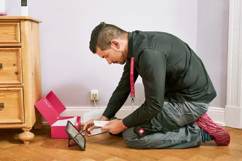 Technik sprawdza instrukcję na tablecie, przygotowując się do instalacji światłowodu. Dowiedz się, ile kosztuje podłączenie światłowodu.