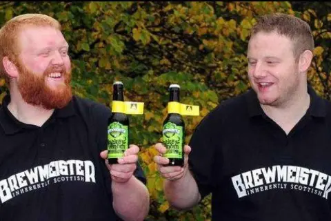 Due uomini sorridono tenendo bottiglie di birra. Potrebbe essere la birra più alcolica del mondo, prodotta da Brewmeister.
