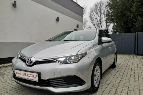 Srebrna Toyota Auris 1.6 benzyna zaparkowana na podjeździe z kostki brukowej.