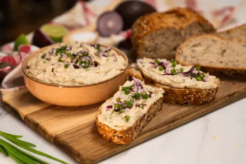 Pyszna pasta z tuńczyka na świeżym chlebie, posypana szczypiorkiem i czerwoną cebulką. Idealna na szybką przekąskę.