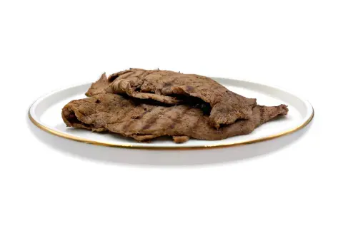 Piatto di paillard di manzo grigliato, sottili fettine di carne con striature scure, servite su un piatto bianco con bordo dorato.