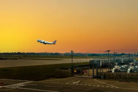 Flugzeug steigt auf vor orangefarbenem Himmel am internationalen Flughafen von London.