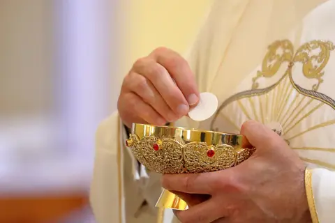 Kapłan w białej szacie z ozdobnym haftem wkłada hostię do kielicha. Pytanie: czy żyjąc w konkubinacie można przystępować do komunii?