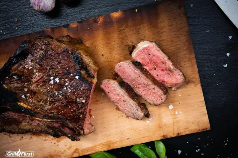 Perfekt gegrilltes T-Bone-Steak, aufgeschnitten, um die ideale Kerntemperatur und saftige Textur zu zeigen.