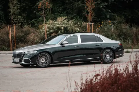 Elegancki Mercedes-Maybach S680 w ciemnozielonym kolorze z dwukolorowym nadwoziem, zaparkowany na tle zieleni.