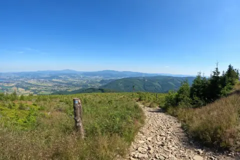 Kamienista ścieżka w polskich górach z widokiem na dolinę i niebieskie niebo.