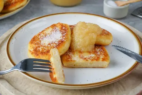 Leckere Quarkkeulchen, goldbraun gebraten und mit Apfelmus und Puderzucker bestreut. Ein perfektes Quarkkeulchen Rezept für Genießer.