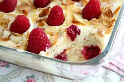 Un délicieux tiramisu framboise, garni de fruits rouges frais et d'amandes effilées, prêt à être dégusté.