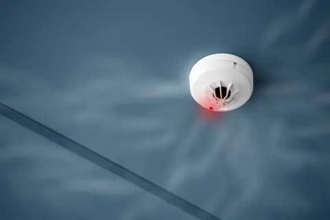 Czujnik dymu na suficie, z czerwoną diodą. Czyżby czad z kominka?