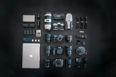 A filmmaker's dream setup, showcasing a serious case of gear acquisition syndrome: cameras, lenses, drone, laptop, and audio gear laid out.