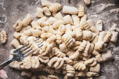 Frische Gnocchi, bereit für köstliche Gnocchi Rezepte, werden mit einer Gabel geformt.