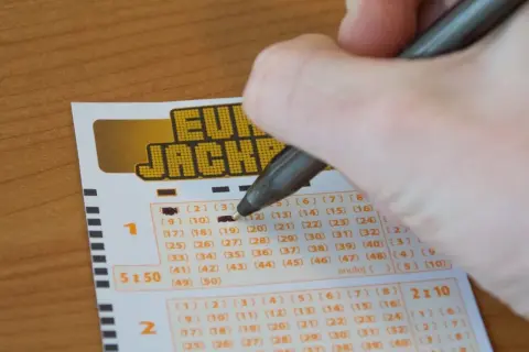Dłoń zaznacza liczby na kuponie Eurojackpot. Zastanawiasz się, jak skreślić Eurojackpot? To proste!