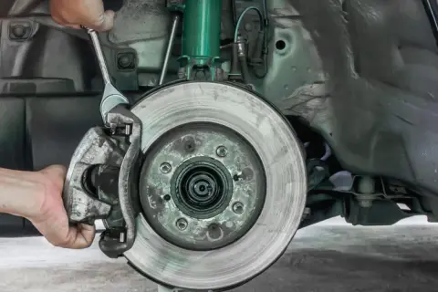 Mechaniker wechselt Bremssattel. Informieren Sie sich über die Bremsen wechseln Kosten für Ihr Fahrzeug.