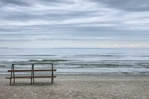 Pusta ławka na plaży w Jelitkowie zaprasza do podziwiania fal. To idealne miejsce na relaks i odkrywanie uroków tego nadmorskiego kurortu.