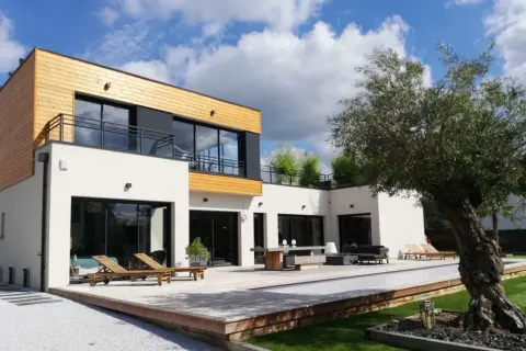 Maison moderne avec piscine et terrasse en bois. On se demande combien de m3 d'eau pour construire une maison comme celle-ci.