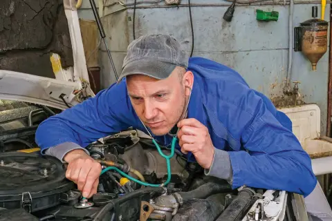 Mechanik z wyspecjalizowanym stetoskopem nasłuchuje pracy silnika, sprawdzając, czy tłoki działają prawidłowo.