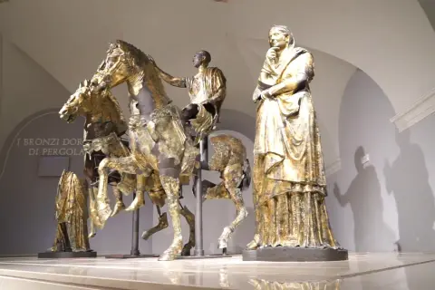 Bronzi dorati di Pergola: un cavaliere su un cavallo, una figura femminile e altre statue antiche.