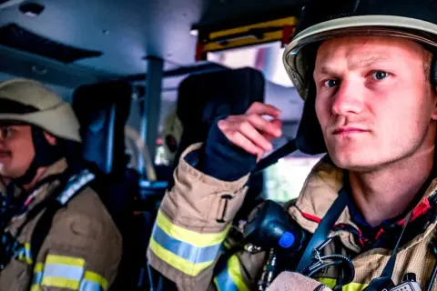 Zwei Feuerwehrmänner in voller Montur, bereit für den Einsatz. Die Serie "Feuer und Flamme Staffel 10" zeigt ihren Alltag.