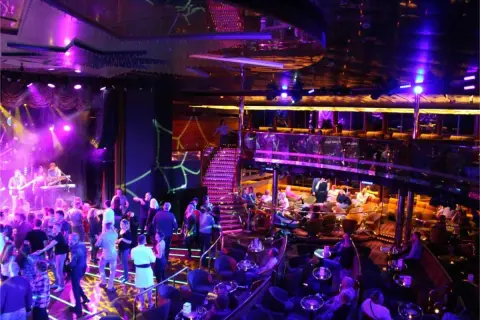 En livlig scen med ett band som spelar, folk som dansar och sitter vid bord. En trappa leder upp till en annan nivå. En typisk bild av stockholm nightlife.