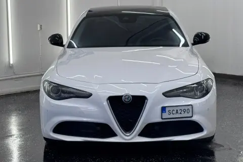 Vit Alfa Romeo Giulia, en elegant begagnad bil med mörk tak och svarta backspeglar. Perfekt för dig som söker stil och prestanda.