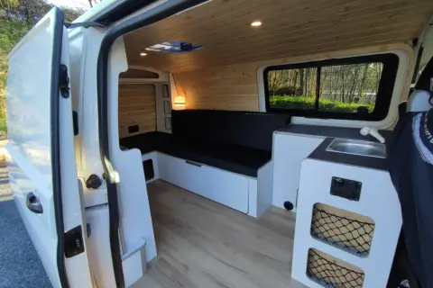Interior de una Volkswagen T5 camperizada con asientos, cama, fregadero y armarios. Lista para viajar.