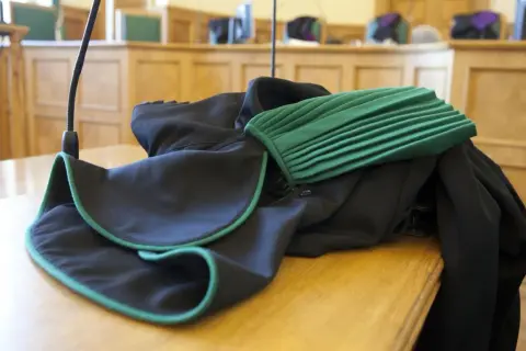 Toga adwokacka na stole w sali sądowej. Zastanawiasz się, ile zarabia adwokat z urzędu?